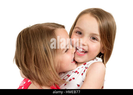 Portrait of cheerful twin sisters hugging , rire, embrassant et souriant à la caméra dans un studio photo. Isolated on white Banque D'Images
