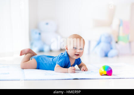 Mignon bébé garçon sur tapis colorés et d'une salle de sport, jouer avec les jouets hochet. Et d'activités pour les enfants centre de jeux pour le développement précoce Banque D'Images