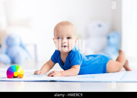 Mignon bébé garçon sur tapis colorés et d'une salle de sport, jouer avec les jouets hochet. Et d'activités pour les enfants centre de jeux pour le développement précoce Banque D'Images