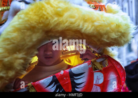 Un jeune garçon chinois en tête de dragon à la tête d'une procession dans les rues de la capitale, au cours de la nouvelle année chinoise. Banque D'Images