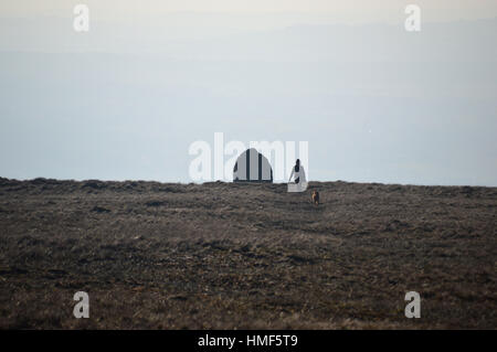 Woman Walking Dog de la pierre sèche du scoutisme sur Memorial Bee Hive Pendle Hill. Lancashire England UK. Banque D'Images