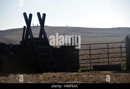 Deux Fellwalkers et Échelle en bois Stile sur muret de pierres sèches près du sommet de la colline de Pendle Lancashire England UK. Banque D'Images