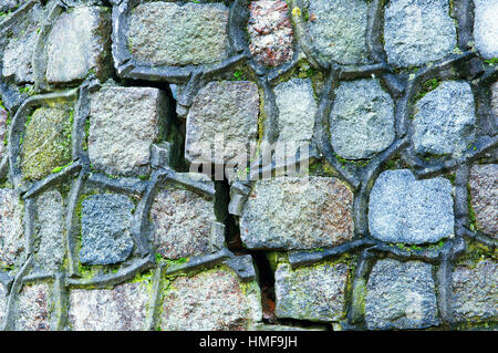 Une fissure dans le mur, couvert de mousse verte le vieux mur de pierre Banque D'Images
