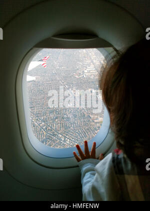 Bébé curieux sur l'avion en regardant par la fenêtre pour la première fois Banque D'Images