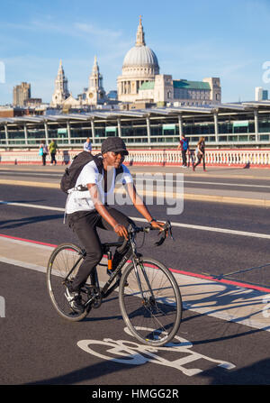 Cycliste féminine équitation sur autoroute cycle nord-sud (CS6) sur Blackfriars Bridge, Londres, avec la cathédrale St Paul en contexte le jour d'été Banque D'Images