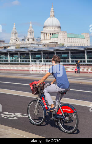 Jeune homme équitation Santander voitures vélo sur autoroute cycle nord-sud sur Blackfriars Bridge, Londres, avec la cathédrale St Paul en arrière-plan Banque D'Images