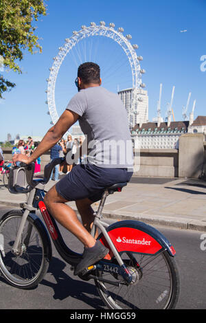 Cycliste masculin sur Santander voitures vélo sur l'autoroute de cycle est-ouest avec London Eye en arrière-plan sur un week-end d'été ensoleillé dans le centre de Londres Banque D'Images