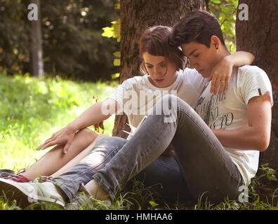 Jeune couple d'étudiants étonnant de lire le livre dans le parc. Soins amour Fashion Concept Banque D'Images