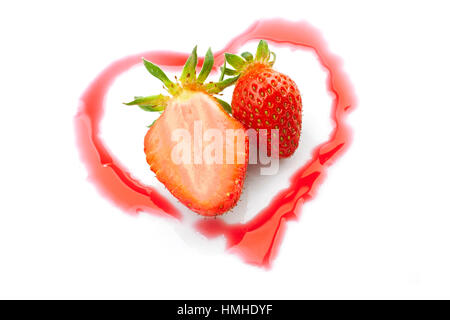 Studio photo gros plan de deux fraises coupées à l'intérieur un demi coeur shinny à partir de sirop de fraise isolé sur fond blanc Banque D'Images