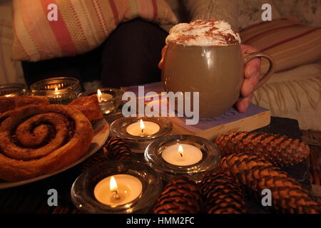 Se détendre dans la soirée aux chandelles dans le hgge coin douillet inspiré d'une maison avec une tasse de cacao, de pâtisseries danoises et d'un bon livre Banque D'Images