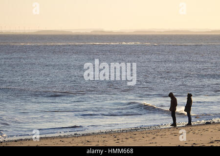 Un jeune couple en train de marcher sur une plage au crépuscule Banque D'Images