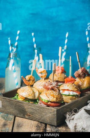 Hamburgers maison en plateau en bois et de la limonade dans des bouteilles en verre Banque D'Images