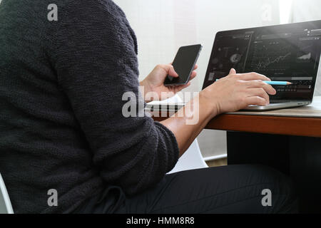 Designer la main à l'aide de paiements mobiles,vente en ligne,crayon omni channel,ordinateur portable sur un bureau en bois in modern office Banque D'Images