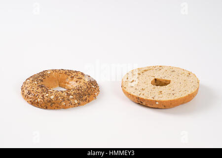 Bagel de moitié avec les graines sur fond blanc Banque D'Images