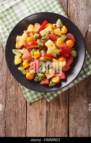 Salade d'orange, kumquat, ananas, carambole, pamplemousse, de prune, de grenade et kiwi close-up sur une assiette. vertical Vue de dessus Banque D'Images