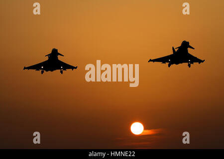 Coucher du soleil sur un soir brumeux à RAF Coningsby comme une paire d'Eurofighter Typhoon RP4s retour d'un déploiement outre-mer en Oman. Banque D'Images