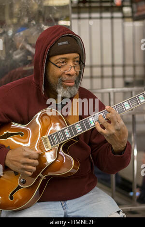 A middle aged African American man jouer la guitare électrique sous terre à la station de métro 34th Street à Manhattan, New York City. Banque D'Images