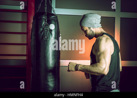 Man practicing boxing sur grand sac noir dans une salle de sport. Banque D'Images