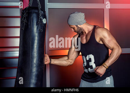 Man practicing boxing sur grand sac noir dans une salle de sport. Banque D'Images