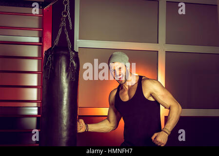 Man practicing boxing sur grand sac noir dans une salle de sport. Banque D'Images