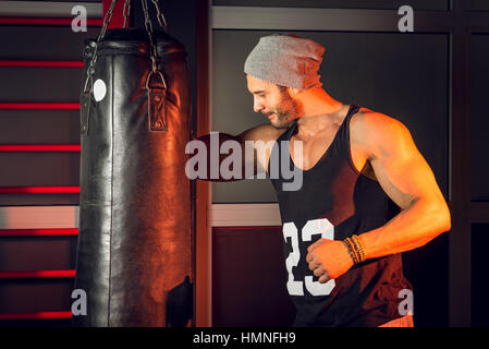 Man practicing boxing sur grand sac noir dans une salle de sport. Banque D'Images