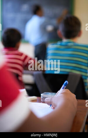 Les jeunes et l'éducation. Groupe d'étudiants hispaniques en classe à l'école pendant la leçon. La main de Deatil écrit sur papier Banque D'Images