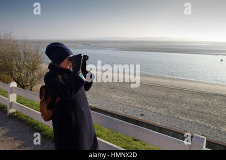 Le Crotoy dans le Nord de l'estuaire de la Baie de Somme France femme avec des jumelles Banque D'Images