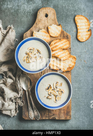 Soupe crémeuse aux champignons dans des bols avec des tranches de pain grillé Banque D'Images