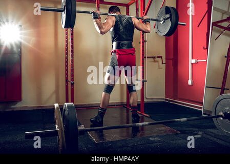 Jeune homme s'accroupit dans l'adolescence de sport à l'club. Banque D'Images