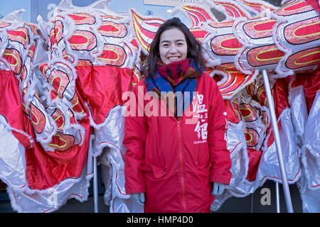 Une belle jeune dame chinoise américaine devant un dragon lors de la Chinese New Years Day Parade à Chinatown, Flushing, New York City. Banque D'Images