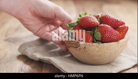 Jeune femme place de bol de fraises sur la table Banque D'Images