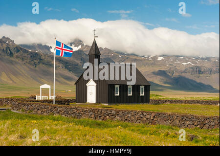 Budir Église à Péninsule de Snæfellsnes, l'Islande, avec l'Islande drapeau, drapeau islandais dans un mât. Banque D'Images