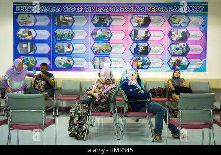 Les femmes sont assises dans une salle d'attente devant une affiche annonçant différents aspects de la santé, car elles attendent d'être vues par les médecins de l'hôpital femmes et enfants de Raja Isteri Pengiran Anak Saleha Hospital (RIPAS) à Darussalam, Brunei. © Time-snapshots Banque D'Images