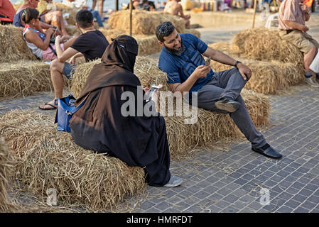 Couple musulman avec une femme en pleine Burka, en utilisant la communication de smartphone tout en se relaxant en vacances. Thaïlande S. E. Asie Banque D'Images