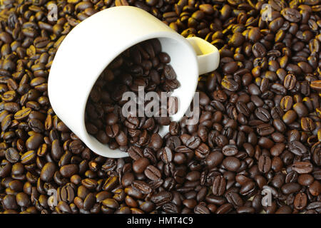 Les grains de café torréfiés tasse blanche renverse. Banque D'Images