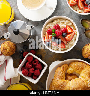 Table de petit-déjeuner avec du porridge d'avoine, de croissants, de fruits frais et de muffins shot Banque D'Images