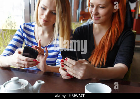 Deux femmes s'amuser au café et à la recherche de téléphone intelligent. Banque D'Images