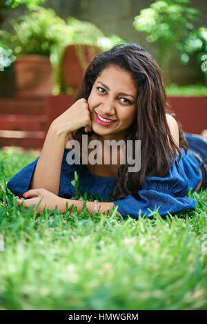 Pretty young girl laying on grass in park Banque D'Images