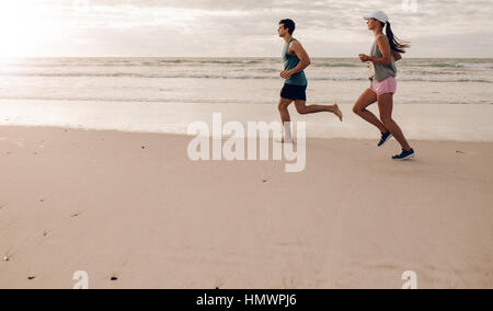 De plein air sur le long de la côte. Young man and woman jogging le matin dans la plage. Banque D'Images