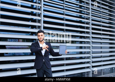 Young handsome businessman musulmans arabes est dans le centre d'affaires en noir élégante robe sur la construction de l'arrière-plan. L'homme d'affaires homme désirant en attente Banque D'Images