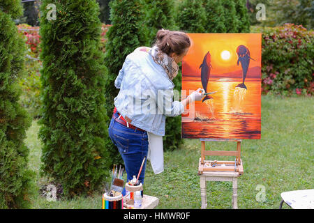 Artiste peinture finitions assez attirantes qui dépeint les dauphins sautant hors de l'eau sur fond orange, les peuplements avec retour à la photographe et beh Banque D'Images