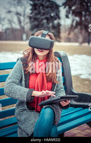 Belle jeune fille avec un casque de réalité virtuelle VR sur la rue intéressé par l'image 360 Banque D'Images