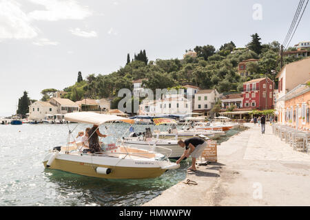 Les touristes l'amarrage d'un bateau de location au petit village de pêche pittoresque de Loggos, Paxos, îles Ioniennes, Grèce Banque D'Images