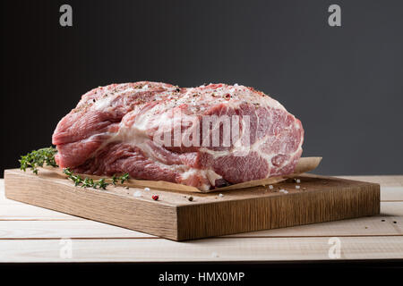 Photo de la viande crue. Cou de porc aux herbes et thym vert sur planche de bois Banque D'Images