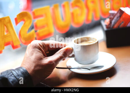 Ein Mann sitzt einem Lokal und hält eine Kaffeetasse in der Hand (Nahaufnahme) Banque D'Images