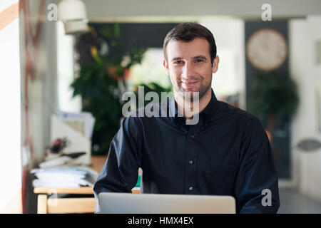 Homme d'affaires prospère de sourire et de travailler sur un ordinateur portable Banque D'Images