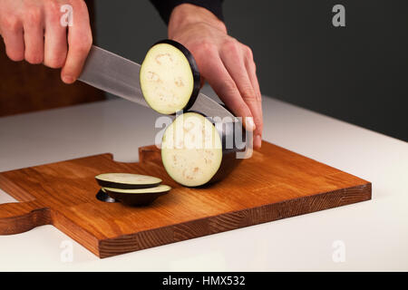 Les tranches d'aubergines mûres sur une planche à découper en bois. Homme aubergine en tranches. Concept de vie sain Banque D'Images