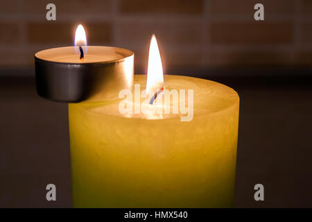 Grande et petites bougies sur fond sombre. Banque D'Images