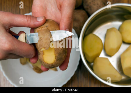 Détail de l'épluchage mains femme de pommes de terre jaunes fraîches avec couteau de cuisine, la préparation des aliments concept. Banque D'Images