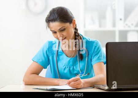 Belle femme médecin écrit à la table in hospital room Banque D'Images